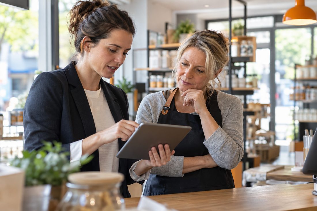 Dans un magasin, une formatrice montre une tablette à une gérante